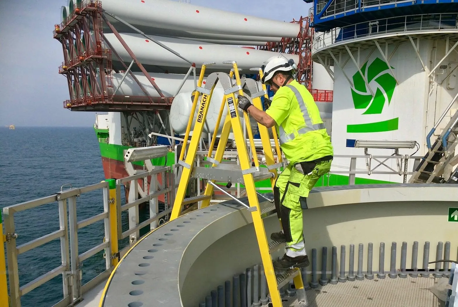 Tecnico al lavoro su una scala a piattaforma BRANACH in vetroresina durante la manutenzione di una turbina eolica